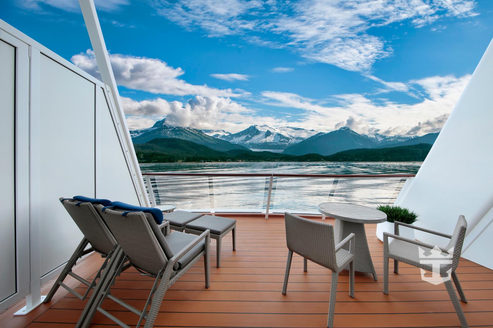 View of the Alaskan mountains and lounge chairs from the balcony of a Grand Loft Suite